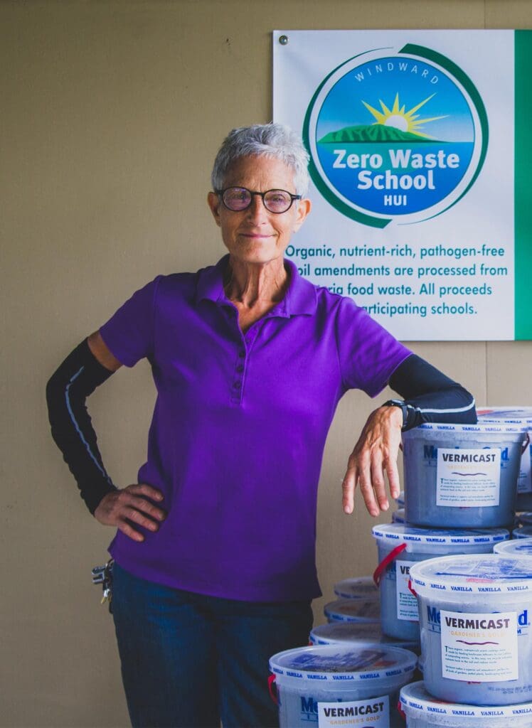 Mindy Jaffe posing in front of the Windward Zero Waste School Hui banner during a compost sale